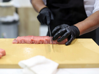 chef experto cortando con cuchillo lomos de atún crudo para elaboración de sushi