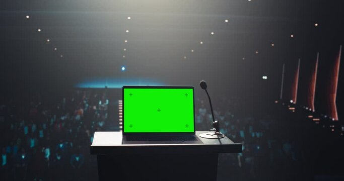 Green Screen Laptop Computer Standing on a Podium at a Conference Hall with Audience in the Background. Template for Business Presentations and Tech Videos, with Room for Custom Content Integration