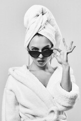 Portrait of a beautiful girl in the studio in a bathrobe and sunglasses. Grain effect used