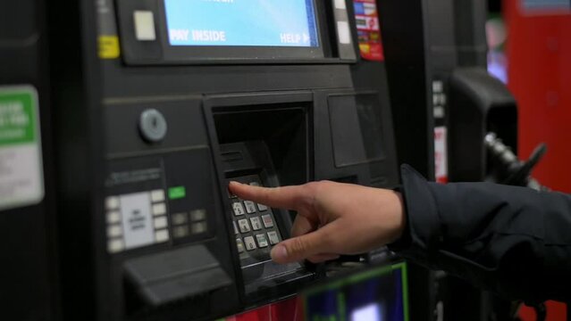 Woman press the pin code on the pay mashinea t the gas station, and wants to pay for fuel