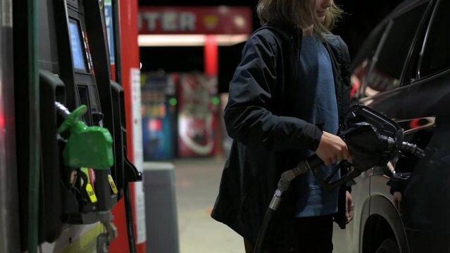 Refueling a car with liquid fuel, connecting a gun to a car tank, A girl pours fuel into her car tank, eco energy, harm to the environment gas emission by a car, Fuel filling station for transport