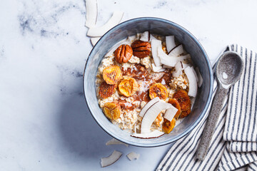 Overnight oatmeal with chocolate, pecans, coconut chips and dried banana, white background.