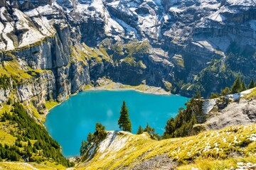 Oeschinensee lake with snow Bluemlisalp mountain on sunny summer day. Panorama of the azure lake...