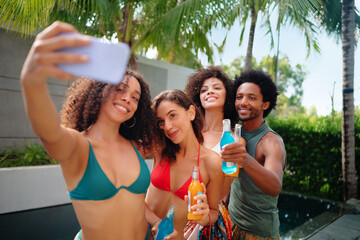 Group of people having fun and taking selfies outdoors in a tropical environment. 