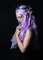 artistic portrait of beautiful female model with long purple hair wearing a fantasy fairy crown and...