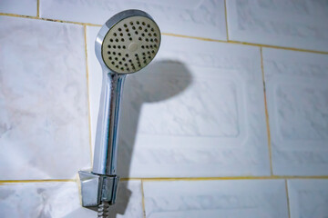 Fototapeta premium Selective focus of old steel shower faucet at white vintage tile background. 
