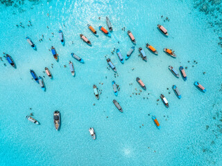 Aerial view of colorful boats, sea bay with transparent azure water on sunny day. Mnemba island, Zanzibar. Top view of sandbank in low tide, blue sea, sand, swimming people, yachts in summer. Ocean