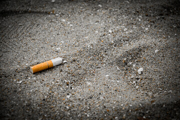 Fag-End or Cigarette butts on the sand at the beach side have a negative effect on the marine environment for no smoking concept on a dark vintage tone background.