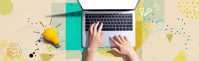 Person using a laptop computer and a light bulb - Flat lay