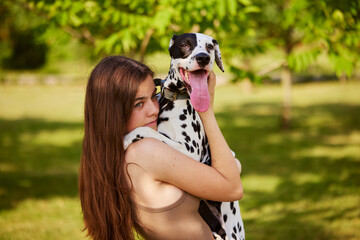 a young girl plays with a dalmatian in the park. dog care concept