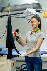 professional dry cleaning young girl irons a black sweater on hanger with steam