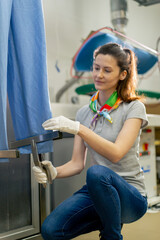 Obraz premium professional dry cleaner young girl takes a suit out of the dryer for finishing by hand press