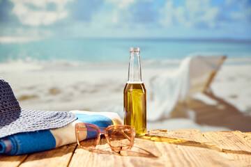 Beachside refreshment. Beer bottle with hat and towel on beach with beautiful ocean view. Concept of summer, vacation, relaxation, travelling, leisure time