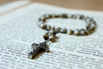 Rosenkranz Kette mit Kreuz und religiöser Text aus einem Gebetstuch der Bibel symbolisieren das...