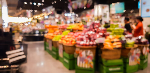Abstract blurred supermarket aisle with colorful shelves and unrecognizable customers as background.