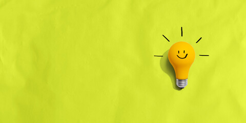 Yellow light bulb with happy face - flat lay