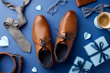 Top view of Father's Day gifts featuring shoes, ties, and a cup of coffee on a dark blue...