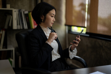 A woman in a business suit is looking at her cell phone