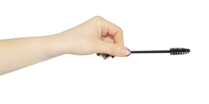 eyelash brush in hand, outstretched hand with eyelash brush isolated from background