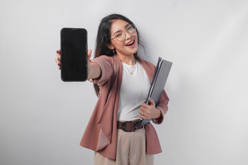 Naklejka premium Beautiful Asian business woman in eyeglasses holding a document presenting copy space on her phone screen, isolated by white background.