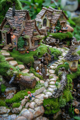 Obraz premium An enchanting fairy garden adorned with whimsical miniature houses, winding pathways, and lush greenery, inhabited by tiny figurines.