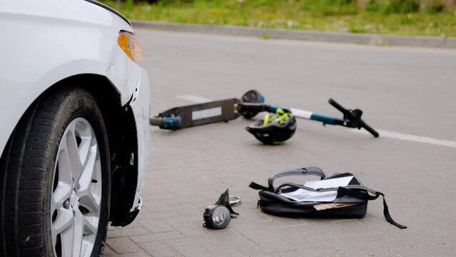 Following accident between automobile and e-scooter damaged scooter lying down asphalt aftermath of automobile incident. Automobile accident electric scooter lies e-scooter repercussions collision.