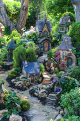 Fototapeta premium An enchanting fairy garden adorned with whimsical miniature houses, winding pathways, and lush greenery, inhabited by tiny figurines.