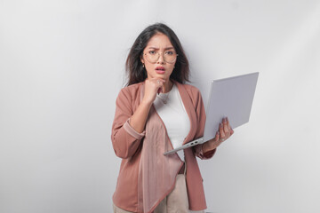 Thoughtful young Asian business woman in eyeglasses with a laptop thinking about work, isolated by white background.