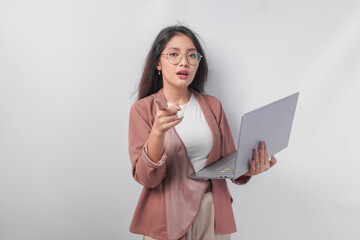 Serious young Asian business woman holding a laptop pointing to the camera, isolated by white background.