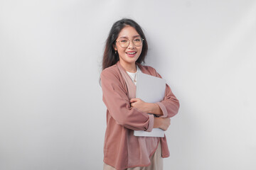 Attractive young Asian business woman holding a laptop close while smiling happily over isolated white background.