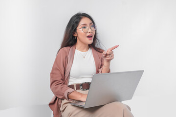 Beautiful young Asian business woman sitting down with a laptop doing interview, isolated by white background.