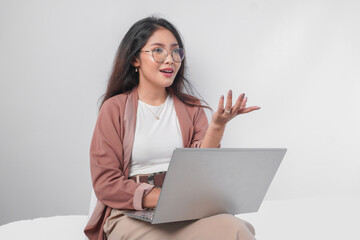 Serious young Asian business woman sitting down with a laptop while having discussion meeting, isolated by white background.