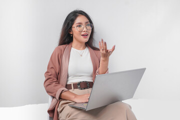 Serious young Asian business woman sitting down with a laptop while having discussion meeting, isolated by white background.