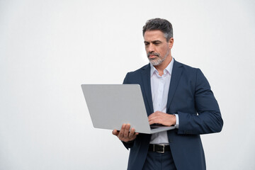 Serious handsome latin older man in formal suit holding desktop computer. Portrait of focused middle age mature businessman using pc laptop for business work. Isolated white background, copy space