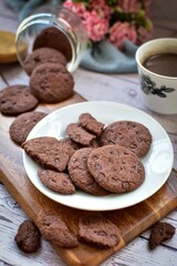 Double choc,chocolate chip cookie on white plate with hot cocoa