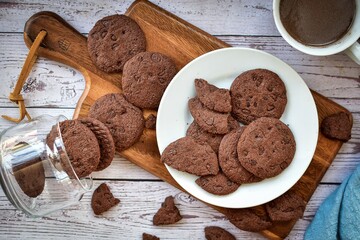 Double choc,chocolate chip cookie on white plate with hot cocoa