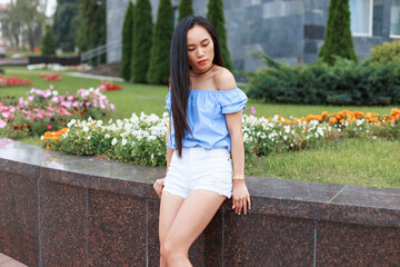 Beautiful summer young Chinese woman in fashion summer clothes with top and shorts outdoors