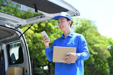 荷物を持ちスマホを見る配送ドライバーの男性