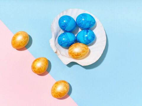 Creative layout with colored easter eggs arranged in a seashell on bright blue and pink background