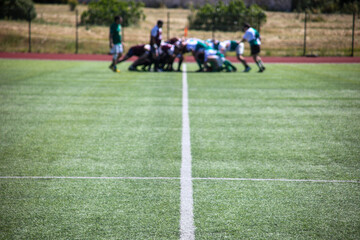 Group of men playing rugby on grass field, tackling and passing ball in action-packed match.