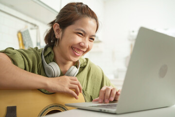 Cheerful Asian Woman playing acoustic guitar Enjoy Online Interaction or Learning Experience on...