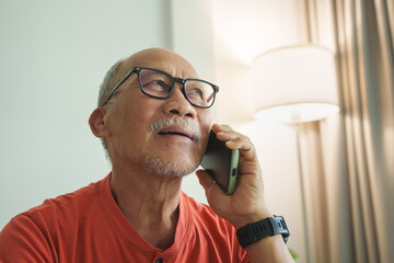 Smiling Elderly Asian Man Enjoying a Pleasant Conversation on His Mobile Phone.