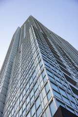 Upward view of modern skyscraper against blue sky
