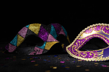 Close-up view of Masquerade mask with confetties on black background.
