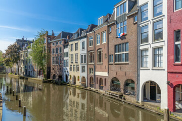 High canal houses in a curve along the Oudegracht canal in Utrecht. A blue sky.