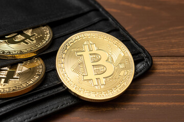 Cryptocurrency bitcoin gold coins in wallet on wooden background.