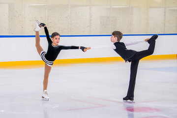 Obraz premium A boy and girl ice skaters are performing a routine on the ice.