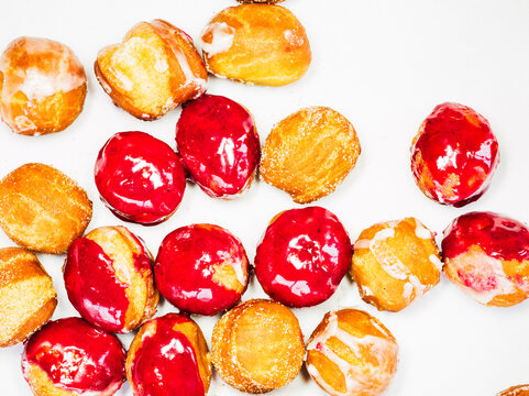 Brown and red glazed donut holes on white paper