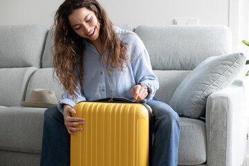 happy girl closing her suitcase at home