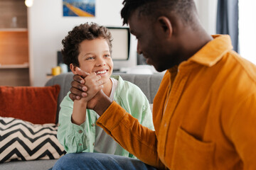 Smiling, positive family, little boy and his African American father spending time together, talking
